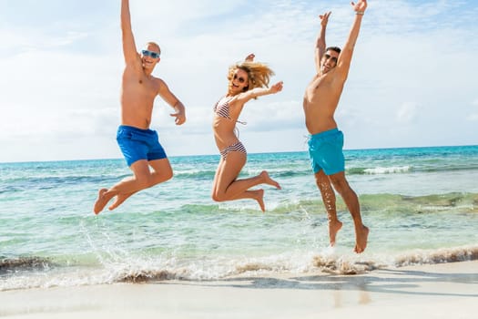 Group of laughing young people on the beach in summer holiday leisure lifestyle
