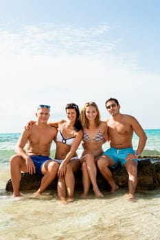 Group of laughing young people on the beach in summer holiday leisure lifestyle