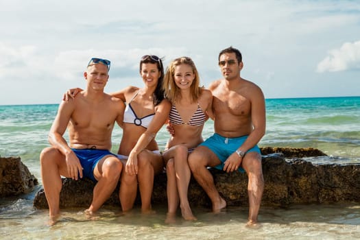 Group of laughing young people on the beach in summer holiday leisure lifestyle