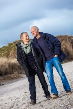 Older adult senior couple walking on the beach lifestyle happy healthy