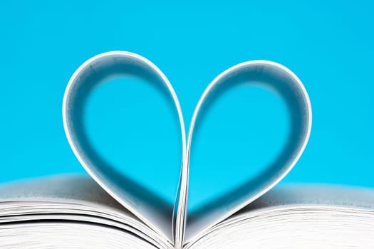 Book folded into a heart shape over a blue background