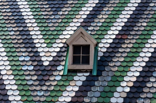 Detailed view of colorful roof shingles and window.