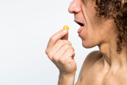 Cropped shot of bare chested mediterranean man taking colourful pill