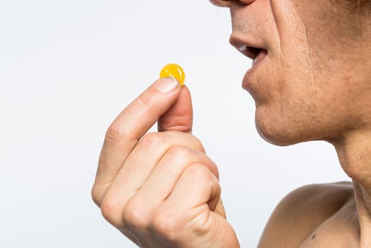 Cropped shot of bare chested mediterranean man taking colourful pill