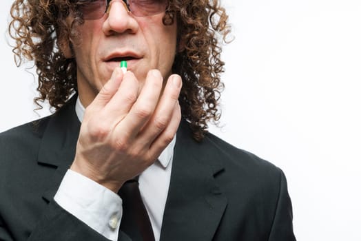 Cropped shot mediterranean man in a suit taking colourful pill