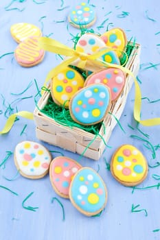 Colorful cookies in Easter nest on blue wood background
