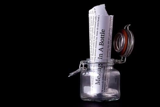 Message in a bottle paper note inside a glass jar with a black background
