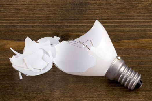 Broken incandescent light bulb on a wooden table