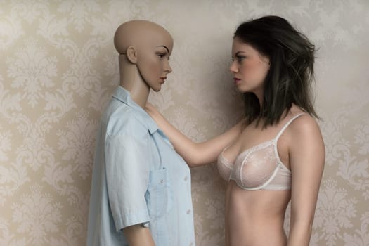 Beautiful young model with a mannequin standing face to face as she models a sexy see-through bra