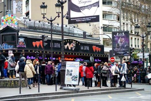 Paris,France – January 01,2014: Tourists stand at an intersection on Boulevard de Clichy in front of an erotic shop in Paris on January 1,2014.