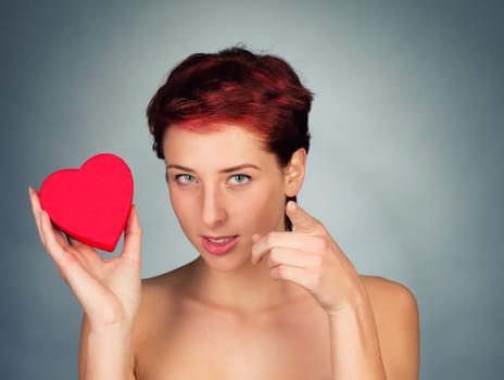 Young woman with a red heart points finger