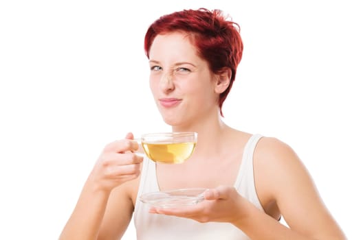 Young woman with tea grimaces against a white background