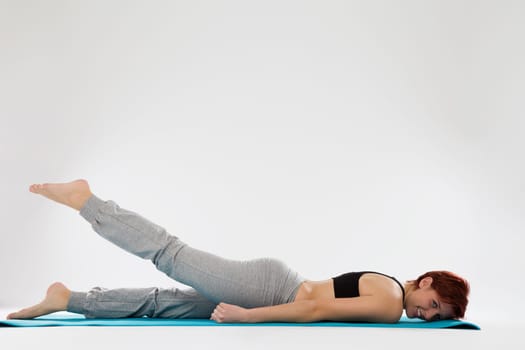 Young woman in fitness exercises trains her legs