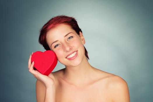 Young happy woman holds Red Heart to her cheek