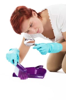 Young woman with a magnifying glass and broom and shovel looking for dirt