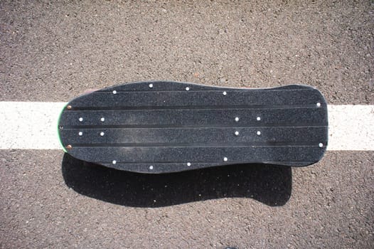 Vintage Style Longboard Black Skateboard on an Empty Asphalt Desert Road
