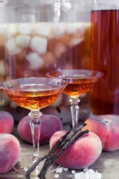 Close-up of homemade vineyard peach liqueur in liqueur jars surrounded by fruit