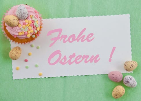 Small colorful cupcake with Easter eggs on a green background