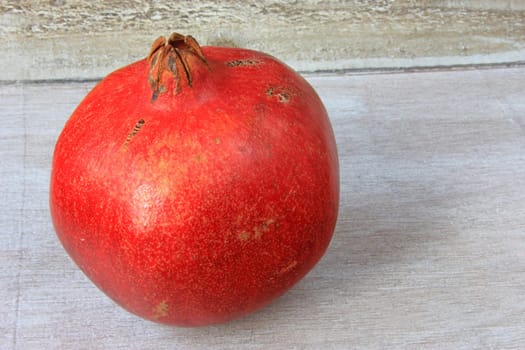 Ripe pomegranate (Punica granatum) on an old,grey wooden tray