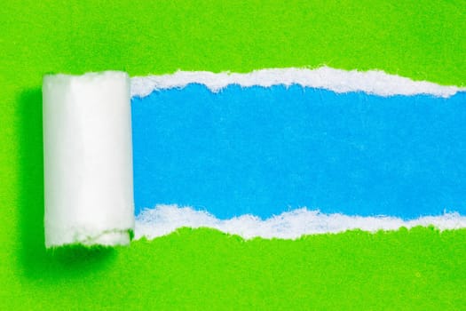 Torn green color paper on blue color background with space for text