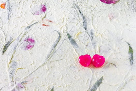 2 red heart candy on mulberry paper surface for sweet, love, romance, classic work. Pastel color background