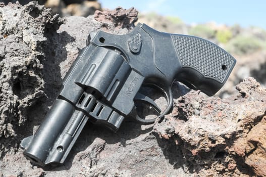 Plastic Revolver Gun Toy on the Volcanic Rocks