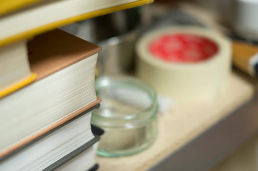 Shelf with art supplies and books,tape and an empty glass bowl