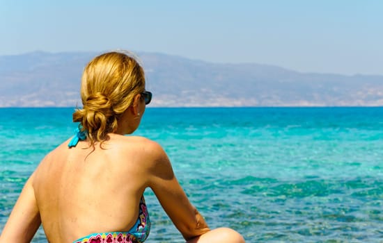 Beautiful young woman in swimsuit, relaxing on a tropical sunny beach