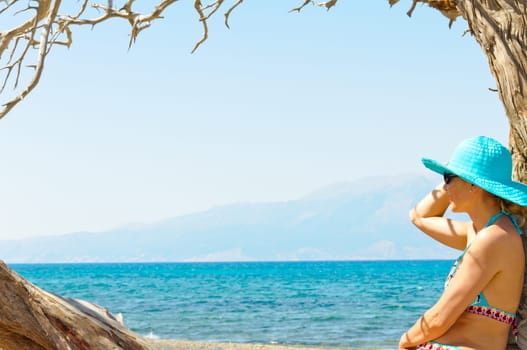 Beautiful young woman in swimsuit, relaxing on a tropical sunny beach