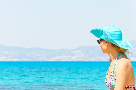 Beautiful young woman in swimsuit, relaxing on a beautiful sunny  beach