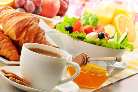 Breakfast with coffee, orange juice, croissant, egg, vegetables and fruits
