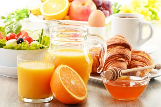 Breakfast with coffee, orange juice, croissant, egg, vegetables and fruits