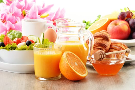 Breakfast with coffee, orange juice, croissant, egg, vegetables and fruits