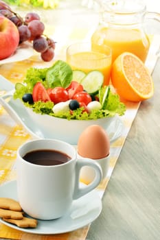 Breakfast with coffee, orange juice, croissant, egg, vegetables and fruits