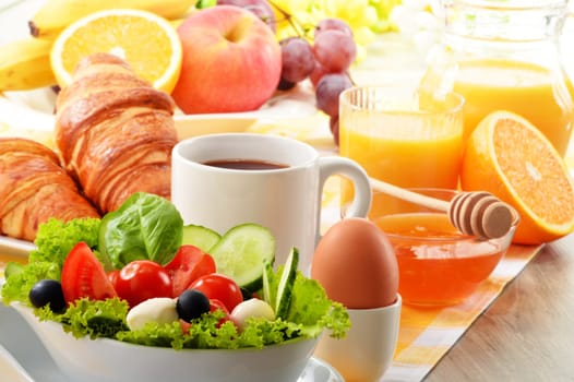 Breakfast with coffee, orange juice, croissant, egg, vegetables and fruits
