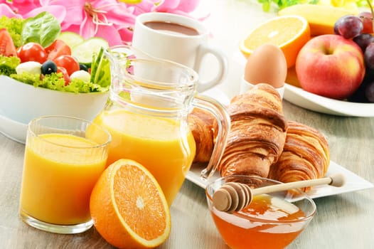 Breakfast with coffee, orange juice, croissant, egg, vegetables and fruits