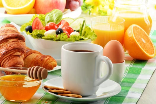Breakfast with coffee, orange juice, croissant, egg, vegetables and fruits