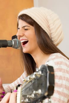 girl singing loud with effort and playing guitar wearing cap