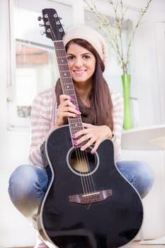 sweet young girl holding the guitar and smiling