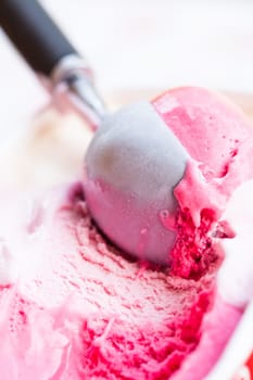 Closeup of raspberry ice cream and metal ice cream scoop