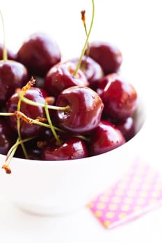 Closeup of bowl of fresh red cherries on light surface