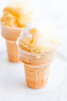 Closeup of two cones of mango ice cream on light background