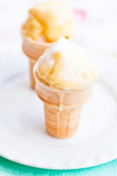 Closeup of two cones of mango ice cream on white plate