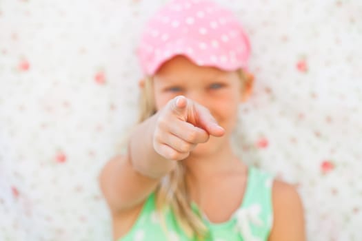 Focus on hand of cute young pointing with finger and looking ahead