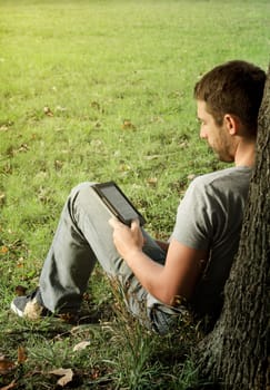 Young man reading e-book in the nature