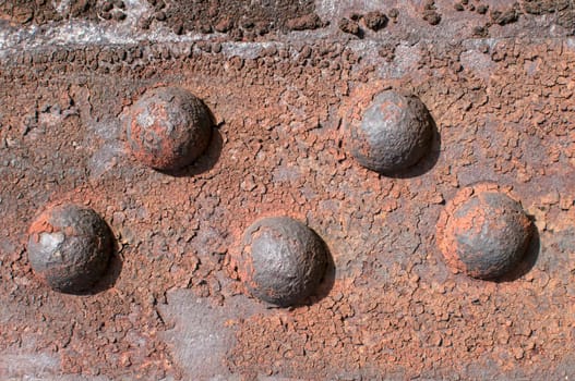 Weathered rusty iron element with centennial rivets link as background