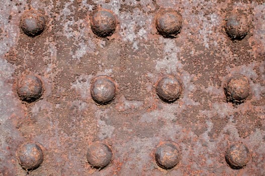 Weathered rusty iron element with centennial rivets link as background