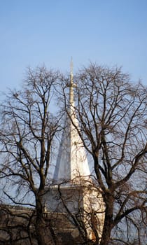 Church tower between bare trees