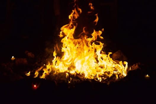 Flames and smoke fill this image of a ceremonial fire during a mayan ritual with a candle in each direction.