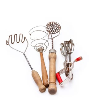 Old cooking utensils,rammers,whisks and hand mixers insulated against a white background